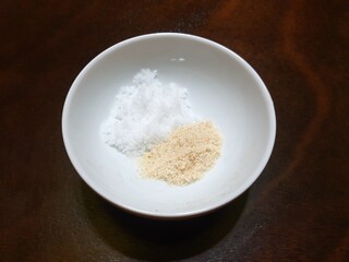 Top view of salt and Chicken powder or Aromat in a white bowl on wooden table as a background, copy space, ready to cooking