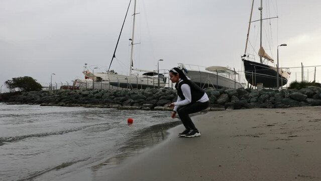 Woman walking on the beach and making photos of the ships in Cyprus port.