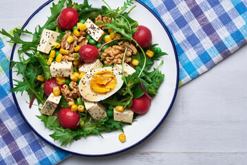 Green salad with tofu and chia seeds. Mixed salad with tofu hazelnuts and tofu on rustic table. Fresh diet salad served in plate.