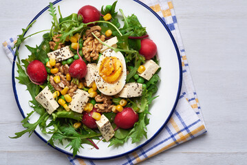 Green salad with tofu and chia seeds. Mixed salad with tofu hazelnuts and tofu on rustic table. Fresh diet salad served in plate.