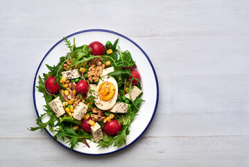 Green salad with tofu and chia seeds. Mixed salad with tofu hazelnuts and tofu on rustic table. Fresh diet salad served in plate.