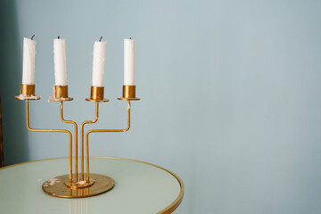 a gold candlestick for four candles on a round table against the background of the wall. elements...