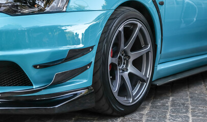 Close up of a wheel of a sports car. Gray car rim with low profile rubber. Blue sports car.