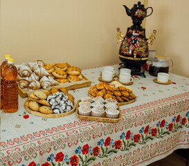 tea table with pies and samovar on a Russian tablecloth