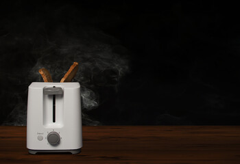 Qualmender Toaster mit verbranntem Toast auf Holztisch