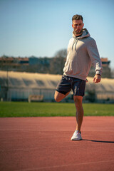 Fototapeta premium A muscular athlete stretches before a sports training session at a sports stadium