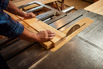 Closeup of wood cutting table with electric circular saw.  Senior Professional carpenter in uniform...