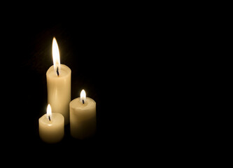 Black template with three candles. Three lit candles in the dark . Black background.
