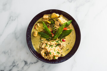 vegan green curry with tofu bell pepper and cauliflower served with brown rice, healthy plant-based food