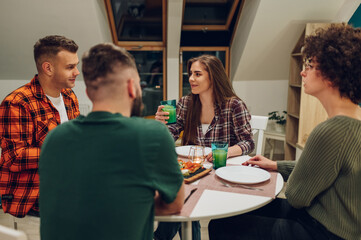 Group of friends enjoying dinner while sitting at the kitchen table together