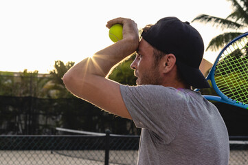 The facial expression of a man tennis player, a male athlete wearing a cap, holds a tennis ball and...