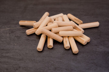 View of a grouping of wooden dowels on grey background. Close-up.