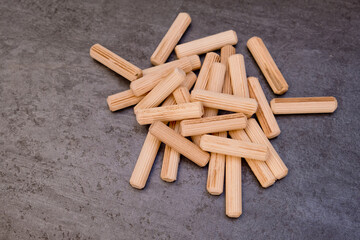 View of a grouping of wooden dowels on grey background. Close-up.