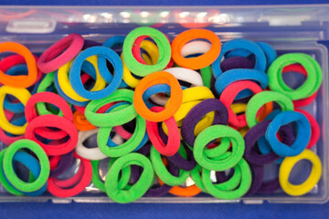 A set of bright multicolored hair bands transparent plastic box on a blue background.