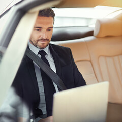 Typing up his proposal on the way into work. Cropped shot of a businessman in the backseat of a car.
