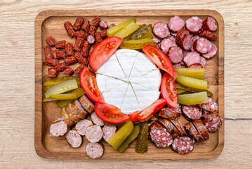 Wooden board with pieces of meat, blue cheese and vegetables, on the kitchen counter, top view.