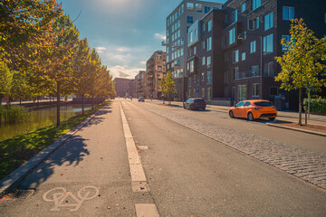 Robert Jacobsens street with trees, bike path, houses and parked cars at sunset. Copenhagen, Denmark