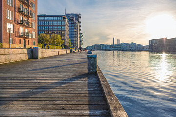 wooden embankment near the water of the canal and residential buildings at sunset. Copenhagen, Denmark - obrazy, fototapety, plakaty
