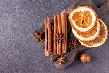 cinnamon sticks, star anise, dried orange on a wooden board, on a blue background, copy space