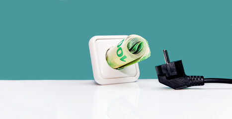 Euro banknotes plugged into the White European plug socket on green background. Concept of saving...