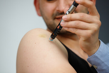 Cropped photo of a man with syringe making insulin injection to himself at home, diabetes and health care concept.