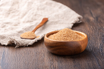 Cane sugar in a bowl and on a spoon over coarse burlap.
