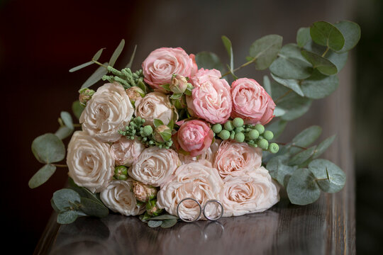 Beautiful wedding bouquet with wedding rings on a wooden table. High quality photo