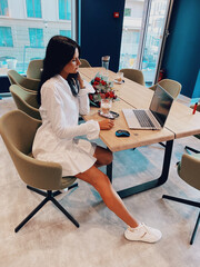 Photo of beautiful smiling young brunette business woman sitting at bright modern work office...