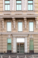 Fototapeta na wymiar Caryatid is supporting balcony on the facade of historical building in Saint-Petersburg, Russia