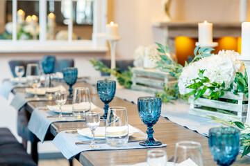 Restaurant table with blue glass, flowers and candles decorated for wedding party