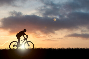 Silhouette of a cyclist in a beautiful evening meadow. bike vacation ideas