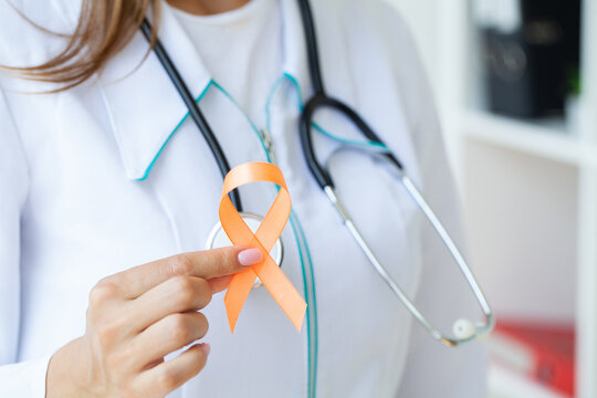 Close up of a doctor holding and showing orange awareness ribbon in her hands