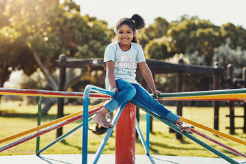 I wish I could play at the park all day. Full length Portrait of an adorable little girl playing on a merry-go-round at the park.