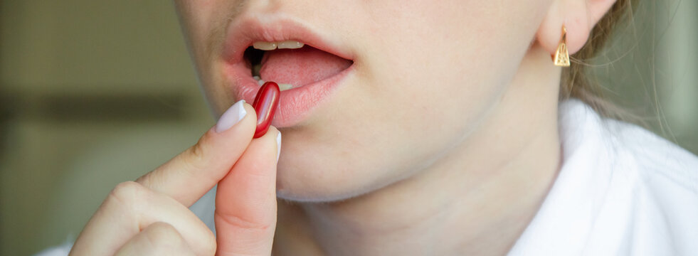 the girl drinks a red pill. close-up photo