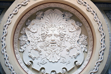 Plaster mask of Dionysus in the ceiling caisson.  A fragment of a coffered ceiling in a historic building with a stucco decoration in the form of a Dionysus mask.  