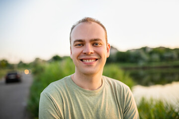 Young smiling guy enjoying nature at sunset. Portrait in the countryside outside the city.