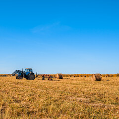 Tractor collecting haystacks in a field