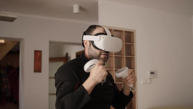 Man At Home Wearing Virtual Reality Headset Holding Gaming Controllers. Active VR Game Virtual Reality Technology Gaming Simulation Helmets. Person Fight Boxing AR Glasses. Metaverse Oculus Technology