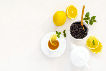 two white cups of tea, black tea brewing, dried tea leaves, fresh mint leaves, lemons whole and pieces, top view, tea drinking, breakfast, ceremony