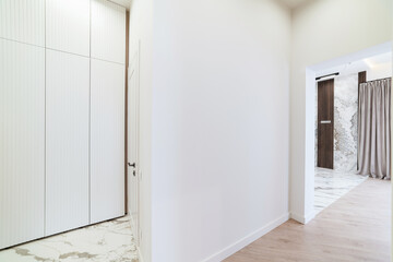 white corridor in the interior of the house with a white closet and a dark floor