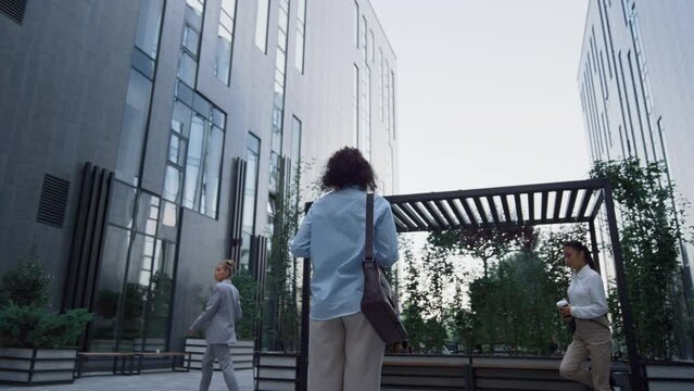 Woman manager standing in downtown area before work in morning. Rear view.