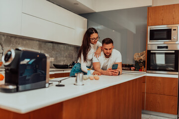 Young happy couple using two phones share social media news at home, smiling husband and wife millennial users customers talking doing shopping online sit at table, mobile tech lifestyle concept