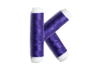 Letter of K from thread spools, isolated on white background. Alphabet concept.