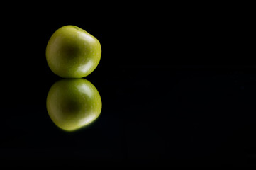 1 Single Juicy green apple with a reflection against a black backdrop beautifully isolated