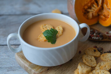 Ripe pumpkin, pumpkin soup puree on a wooden table.