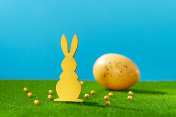 Easter holiday. Wooden rabbit decor. Colored spring eggs on green grass
