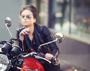 Fototapeta na wymiar Shes an easy rider.... Shot of a young female biker smoking a cigarette.