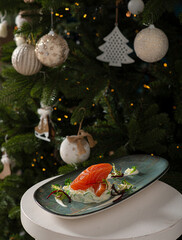Fototapeta na wymiar New Year's Christmas dish of red fish on the background of a decorated Christmas tree