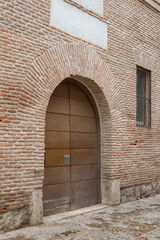 wooden door with a semicircular arch in a brick facade with a window