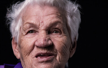 Portrait of an aged woman looking away on a black background